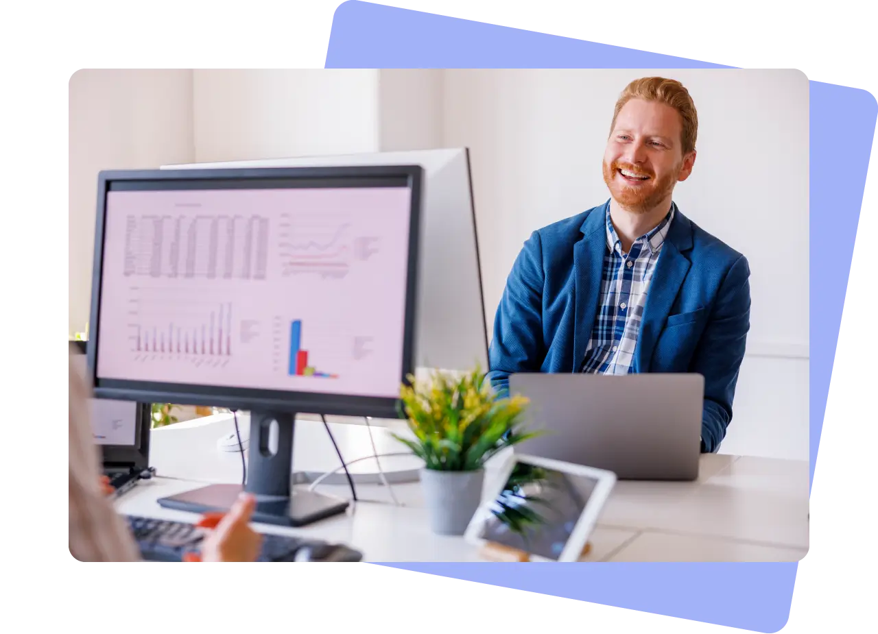 Man laughing behind a computer screen with charts and graphs on it.