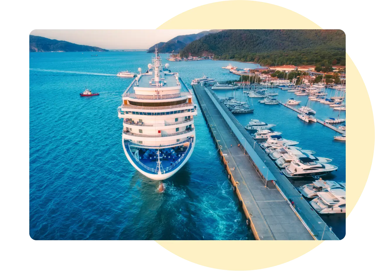 A cruise ship docked at a harbour, surrounded by beautify scenery.