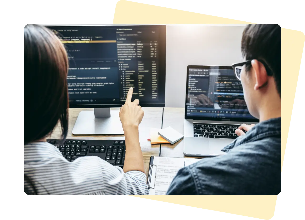 Over the shoulder perspective of a Female and Male web developer working on code on their computers.