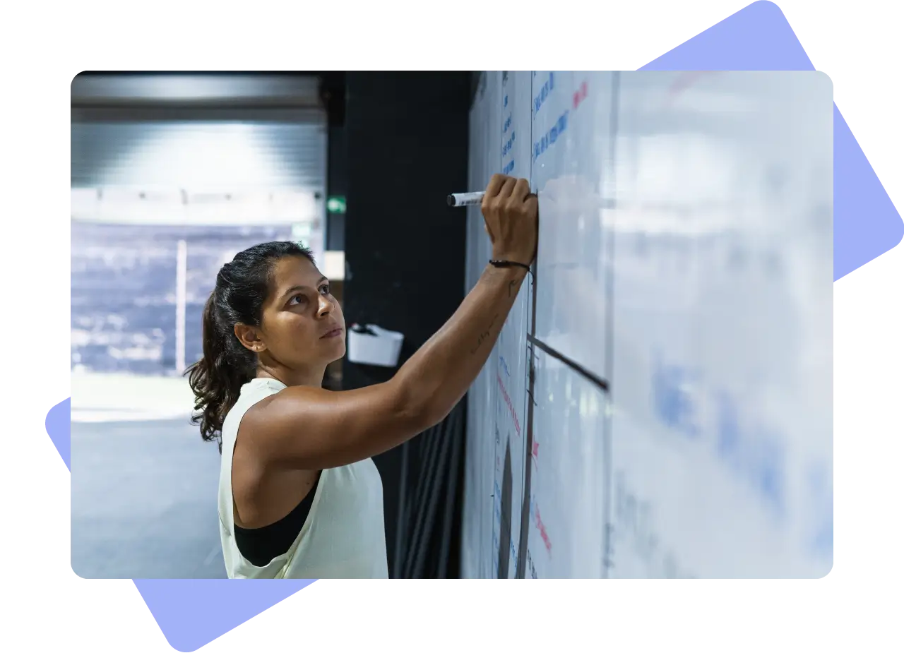 Woman writing on whiteboard.