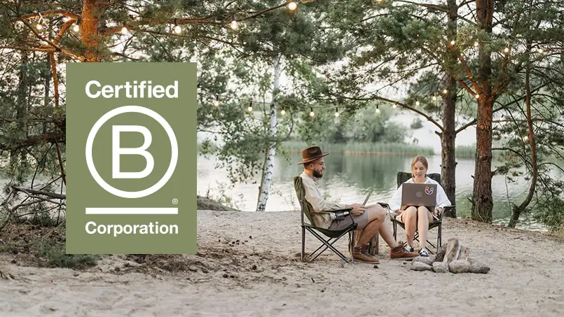 A man and a woman working on laptops in the Australian bush. Behind them is a lake. The B Corp logo is also shown.